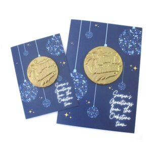 Two Chocolate Christmas Cards featuring blue designs with gold "Merry Christmas" medallions, "Season's Greetings from the Optstone team," and printed hanging ornaments.