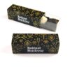 Two black and gold rectangular boxes with "Belfast Harbour" text and festive patterns, one open showing a chocolate treat inside, identified as the Christmas 3 Chocolate Personalised Finger Box.