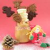 Chocolate Christmas lollipops in a jar of sugar with a pinecone and doll on a red background.
