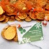 Chocolate coins in net bags with a card that reads, "Merry Christmas & a Happy New Year from all at Breckland Scientific!" on a marble surface.