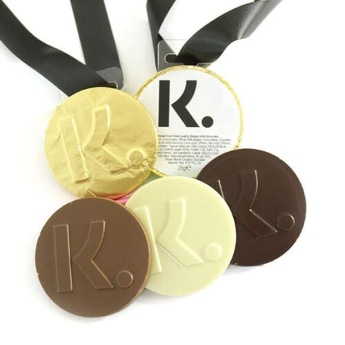 img_0635_-_m2_0724.2 A set of five "K" embossed Bespoke Chocolate Medals, available in gold, brown, and cream hues, finished with black ribbons.