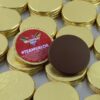 img_1390_-_m2_0724 Stacks of gold foil-wrapped Promotional Chocolate Coins are shown, featuring one unwrapped coin and a wrapper that reads "VALORFEST 2024 #TEAMVALOR.