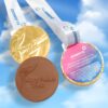 Three Olympic Gold Chocolate Medals featuring the Mary Peters Trust logo and Power NI branding set against a cloudy background.