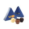 Three truffles sit before two blue pyramid-shaped boxes labeled "UTV," featuring "www.u.tv," part of the Chocolates For Dinner Events line.