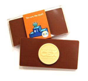 s0436137 Two chocolate bars branded "CEX". One is partly wrapped with a colorful tag saying "You are the best!" and featuring a smiling cartoon character illustration, from the Clear Box holding a Customised Chocolate Bar.