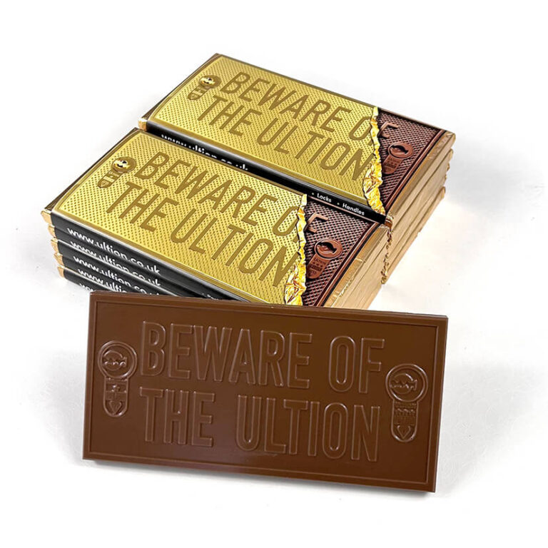 A bespoke chocolate bar with business branding, sitting with two stacks of chocolate bars in full colour corporate branded wrappers. Personalsied business gifts.