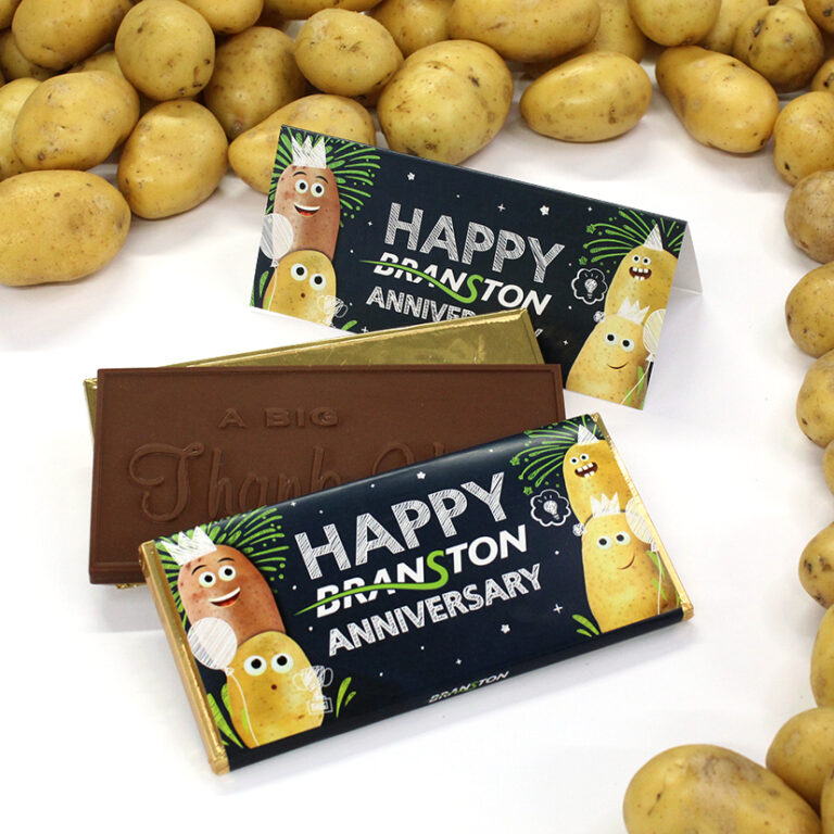 How to design a campaign around branded chocolate with a milk chocolate bar with the message-"A Big Thank You" embossed in the chocolate inside a wrapper with Happy Branston Anniversary design printed on it. The chocolate bars are surrounded by potatoes.